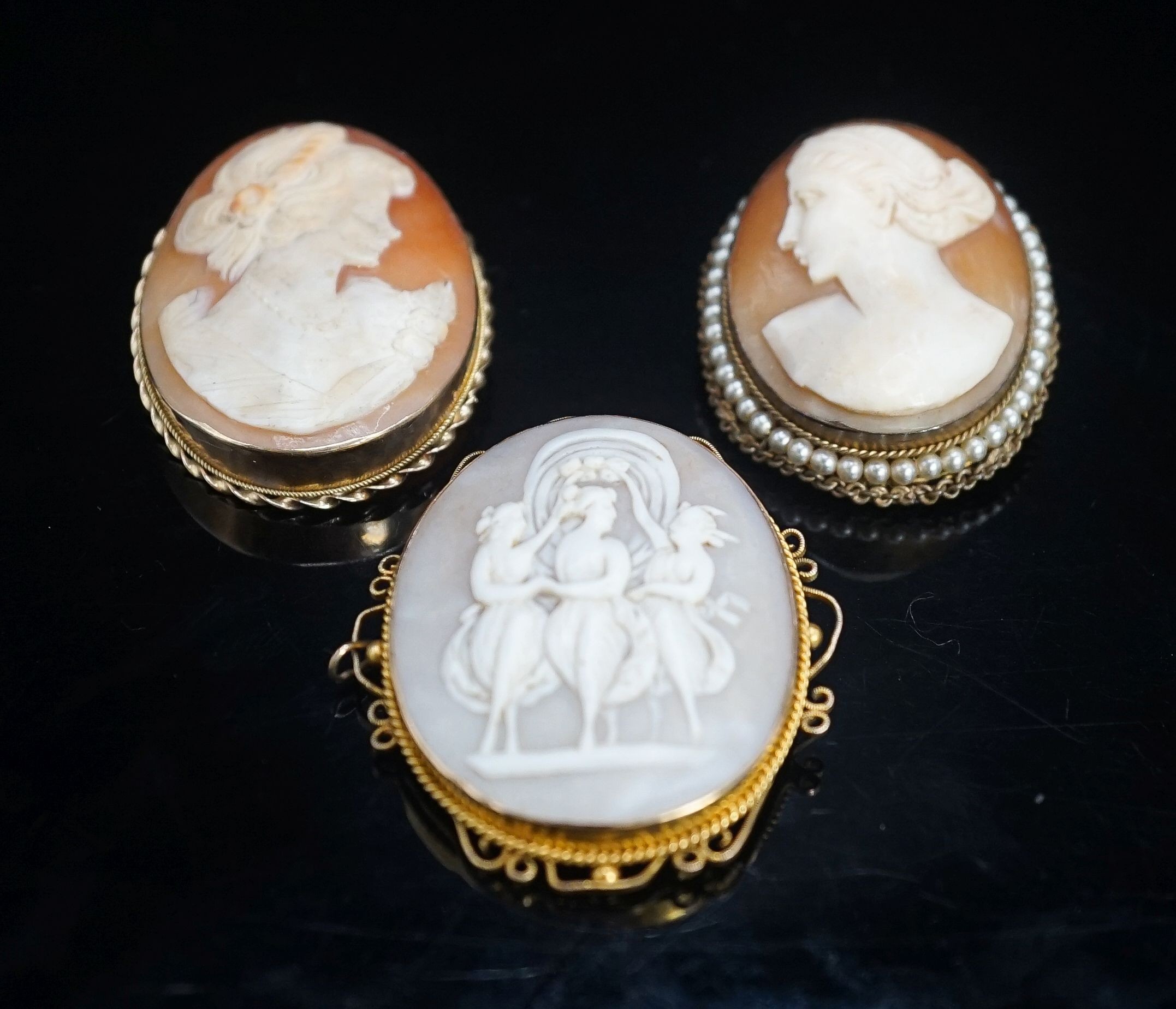 A Victorian 9ct mounted oval cameo shell brooch, one other later 9k mounted cameo brooch and a gilt metal mounted cameo brooch.